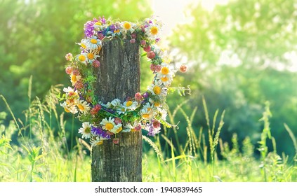 rustic wildflowers wreath on sunny green meadow, natural background. floral traditional decor for Summer Solstice Day, Midsummer holiday. pagan wiccan symbol and rituals