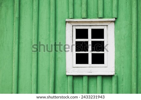 Rustic window in wooden village cottage house. Green wood wall. Countryside architecture background. Small window frame white paint. Empty copy space paint wall. Square shape window.