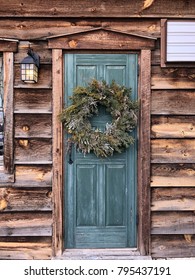 Rustic Wood Home With Blue Green Front Door, Fresh Wreath Hanging On Door