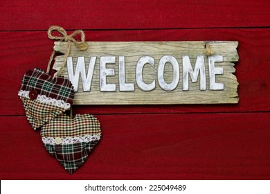 Rustic wood welcome sign with red and green plaid country hearts hanging on dark red barn door - Powered by Shutterstock