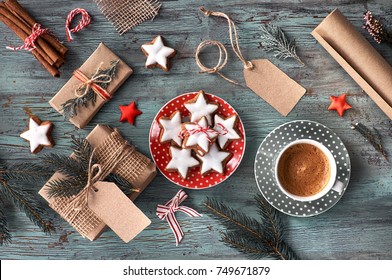 Rustic Wooden Background With Cup Of Hot Coffee And Gift Wrapping Of Christmas Cookies. Seasonal Background Shot From Above. Flat Lay, Top View, Filtered Image. Tag Mockup, Copy Space On The Tags.