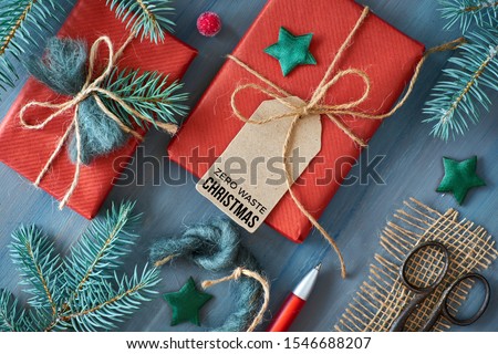 Rustic wooden background with fir branches and Christmas presents gift wrapped in red paper. Ideas for eco friendly decorations. Flat lay, top view, text 