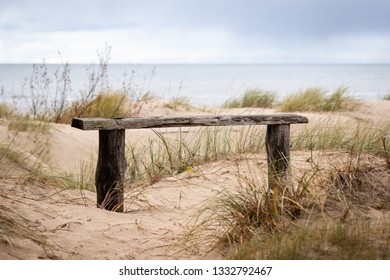 Rustic wooden bench in the dunes of baltic sea. Overcast day at the beach - Powered by Shutterstock