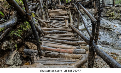 Rustic wooden bridge built from logs alongside a flowing waterfall. - Powered by Shutterstock