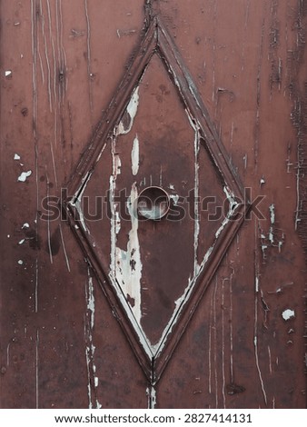 Rustic wooden door texture background. Vintage brown painted door with diamond panel, brass knob, and peeling paint.