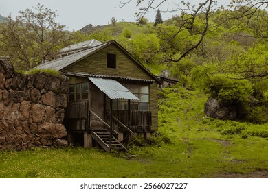 Rustic wooden house surrounded by lush greenery in the Armenian countryside on a cloudy day - Powered by Shutterstock