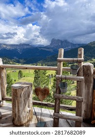 Rustic wooden objects including a ladder and a wooden heart on a fence in front of green mountains on a cloudy day