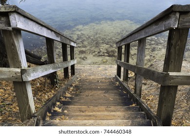 Rustic wooden stairs leading down to small landing at clear fresh water. Autumn scene - Powered by Shutterstock