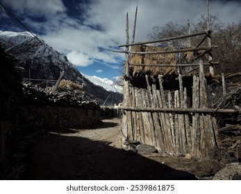 Rustic wooden structure with snow-capped mountain background under dramatic sky. - Powered by Shutterstock