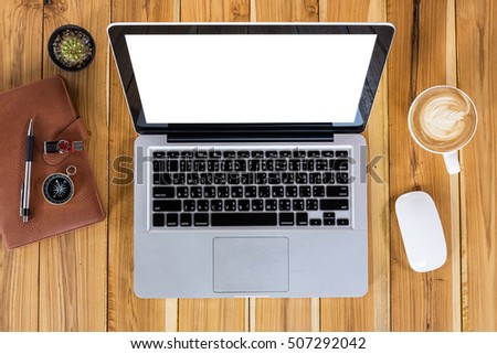 Rustic wooden table with blank screen laptop, pen, eyeglasses and cup of coffee.Top view.Modern office supplies and gadgets.
