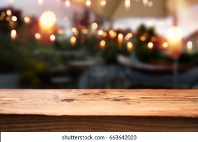 Rustic Wooden Table In A Restaurant With A View Outside On A Night Scene With Light Chains
