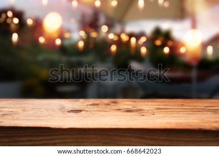 Rustic wooden table in a restaurant with a view outside on a night scene with light chains
