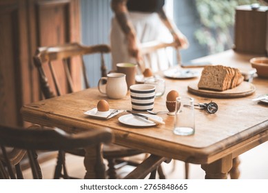 A rustic wooden table is set for a simple breakfast, with eggs, bread, and coffee, creating a warm and inviting atmosphere