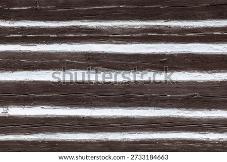 Rustic wooden wall texture showcasing brown logs and white chinking