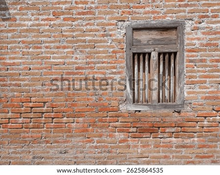 Rustic wooden window with bars set in a weathered red brick wall. Architectural detail, aged texture, vintage feel. Suitable for backgrounds.