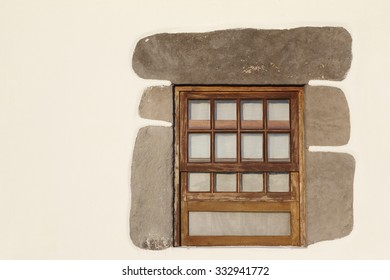 Rustic wooden window with stone frame over a white wall. Horizontal