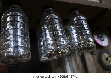 Rustic workshop diy storage solution shows an organized collection of old plastic bottle containers. This resourceful system holds hardware like screw and nail for easy access