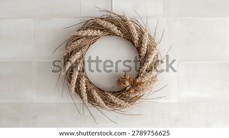 Rustic wreath crafted from dried wheat stalks and natural twigs hanging on a neutral wall. Elegant farmhouse decor with seasonal harvest and autumn styling.