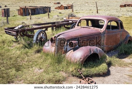 Rusting antique vehicle and wagon in the arid desert landscape of California, USA.