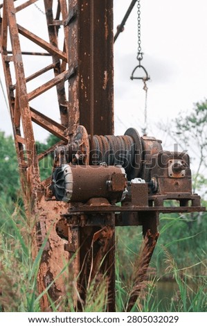 Rusty abandoned boat winch and cable reel on derelict crane structure
