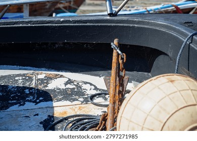 Rusty anchor and spider webs inside a traditional longtail boat. Close-up of weathered boat details showing texture, age and life on a tropical beach in Phuket, Thailand.