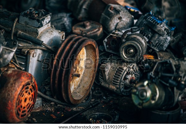 Rusty automobile engines stacked\
in the scrapyard. Engine parts greased and covered with\
rust.\
