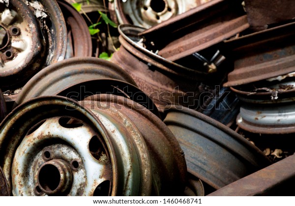 rusty automobile wheel rims in a scrap metal pile\
at an auto wrecker