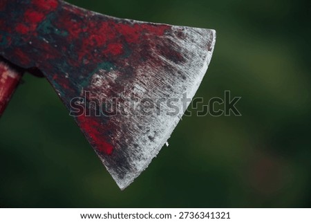 A rusty axe head with a green handle. The axe is old and worn, with a lot of dirt and grime on it. The image has a moody and somewhat eerie feel to it