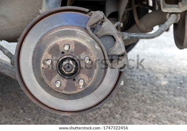 Rusty back car wheel hub with brake disc at tire\
shop. Car without a wheel while replacing on the tire service\
center. Closeup view