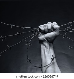 Rusty barbed wire in a strong man's hand - Shutterstock ID 126036749