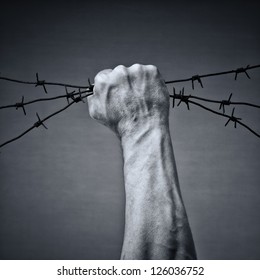 Rusty barbed wire in a strong man's hand - Shutterstock ID 126036752