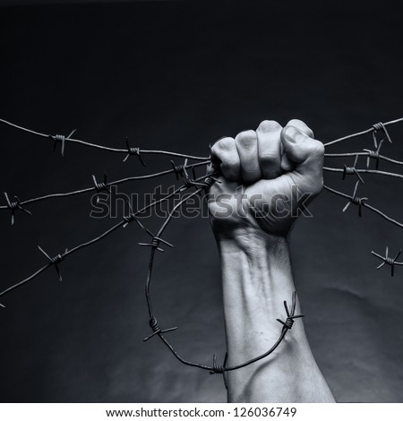 Rusty barbed wire in a strong man's hand