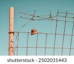 A rusty bell on a wire fence