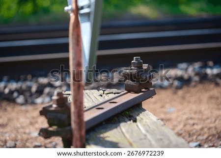A rusty, bent metal hook or hinge on an old, weathered piece of wood