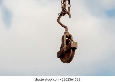 A rusty block hanging from a barn beam against the sky. Lifting loads to the attic (first floor). - Powered by Shutterstock