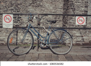 A rusty blue bike parked between 2 parking prohibition signs. Dutch text on 1 of signs says : "Because of safety reaons forbidden to park bikes" - Shutterstock ID 1083536582