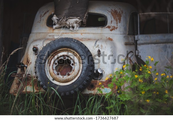 a rusty,
broken-down white car with a spare
wheel