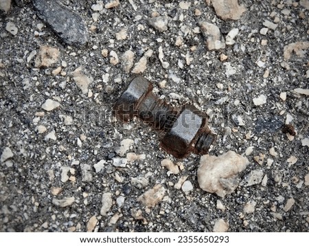 rusty brown bolt with nut imprinted in hardened asphalt with colored granite