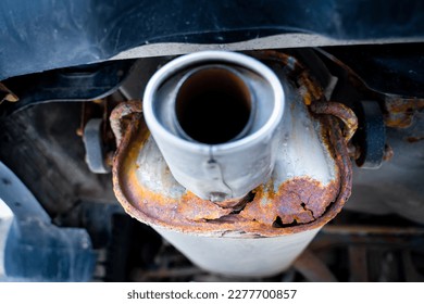 Rusty car exhaust muffler with a through hole, close-up. Corrosion on a metal exhaust pipe after winter. The reaction of salts and reagents in winter on metal parts of a car - Powered by Shutterstock