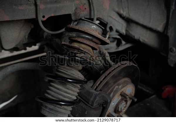 Rusty\
car shock absorber with crushed metal at the\
base