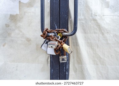Rusty chain with multiple padlocks securing closed storefront doors, symbolizing business closure, security, and urban decline in a city environment.