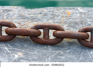 Rusty Chain on a Pier / Close up of a large and rusty chain on a stone background, pier and water