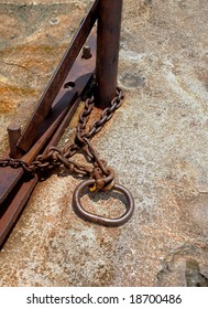 Rusty chain with shackle around a steel pole on a granite stone ground - Shutterstock ID 18700486