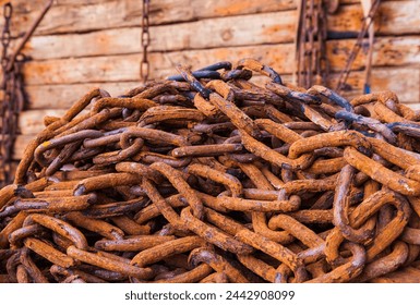 Rusty chains lie on wooden logs and hold them together close-up.