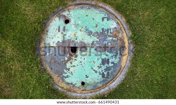 Rusty\
Circular Painted Hole Cover on Grass\
Texture