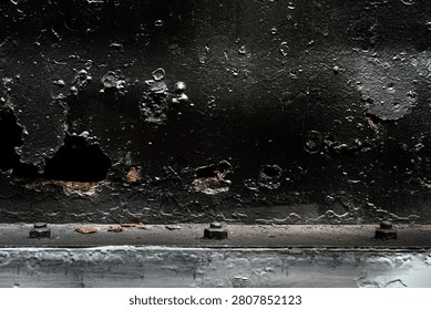 Rusty decayed black metal surface with cracked paint and corroded holes texture. Heavily weathered and corroded black metal plate.  Abstract backgrounds, Vintage themes, Representing neglect and aging