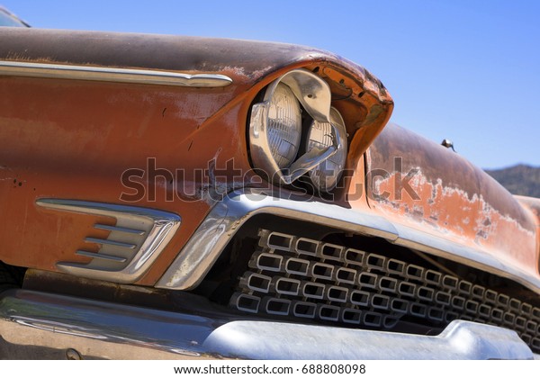 Rusty and dented\
vintage car baking in the sun. Close up detail showing front\
passenger side corner with twin headlight, grill and bumper. (1959\
Mercury Commuter Station\
Wagon)