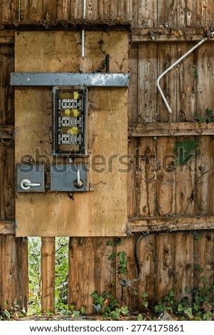 Rusty electrical fuse panel mounted on wooden wall inside derelict barn showing decay, neglect and obsolete infrastructure