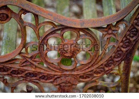 Rusty end of an old bench sitting in the forest.