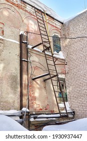 A Rusty Fire Escape On The Wall Of An Old Industrial Building. Winter View.